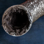 A dirty laundry flexible aluminum dryer vent duct ductwork filled with lint, dust and dirt against a blue background